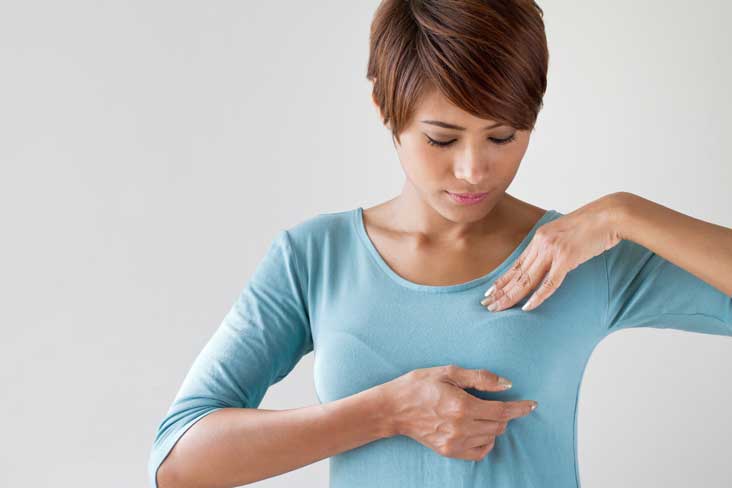 Woman checking her breast for any noticeable changes that may require a visit to a doctor for a further breast examination